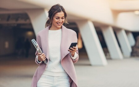 Girl walking in pink jacket holding phone