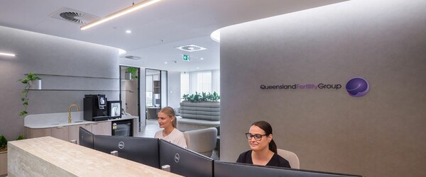 two receptionists looking at screen smiling in new fertility clinic
